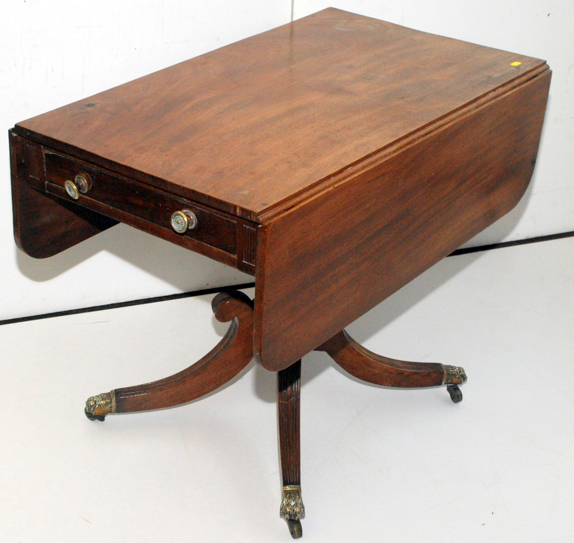 A Regency mahogany Pembroke table with turned pedestal on moulded quadruple base with wave knees,