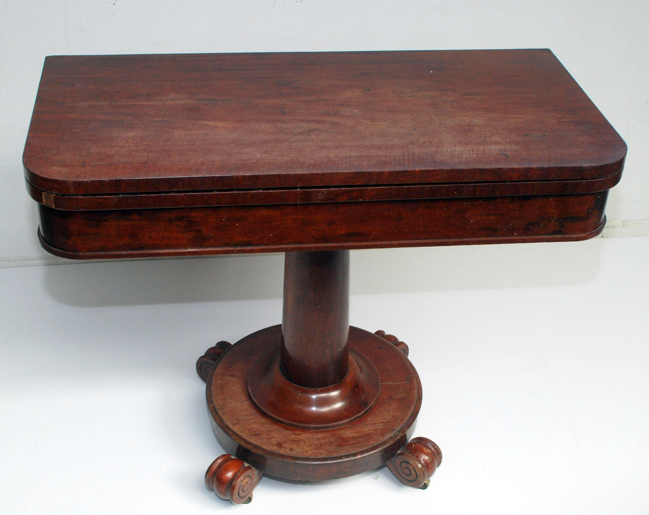 A fold top Victorian mahogany card table with vase pedestal and claw feet.