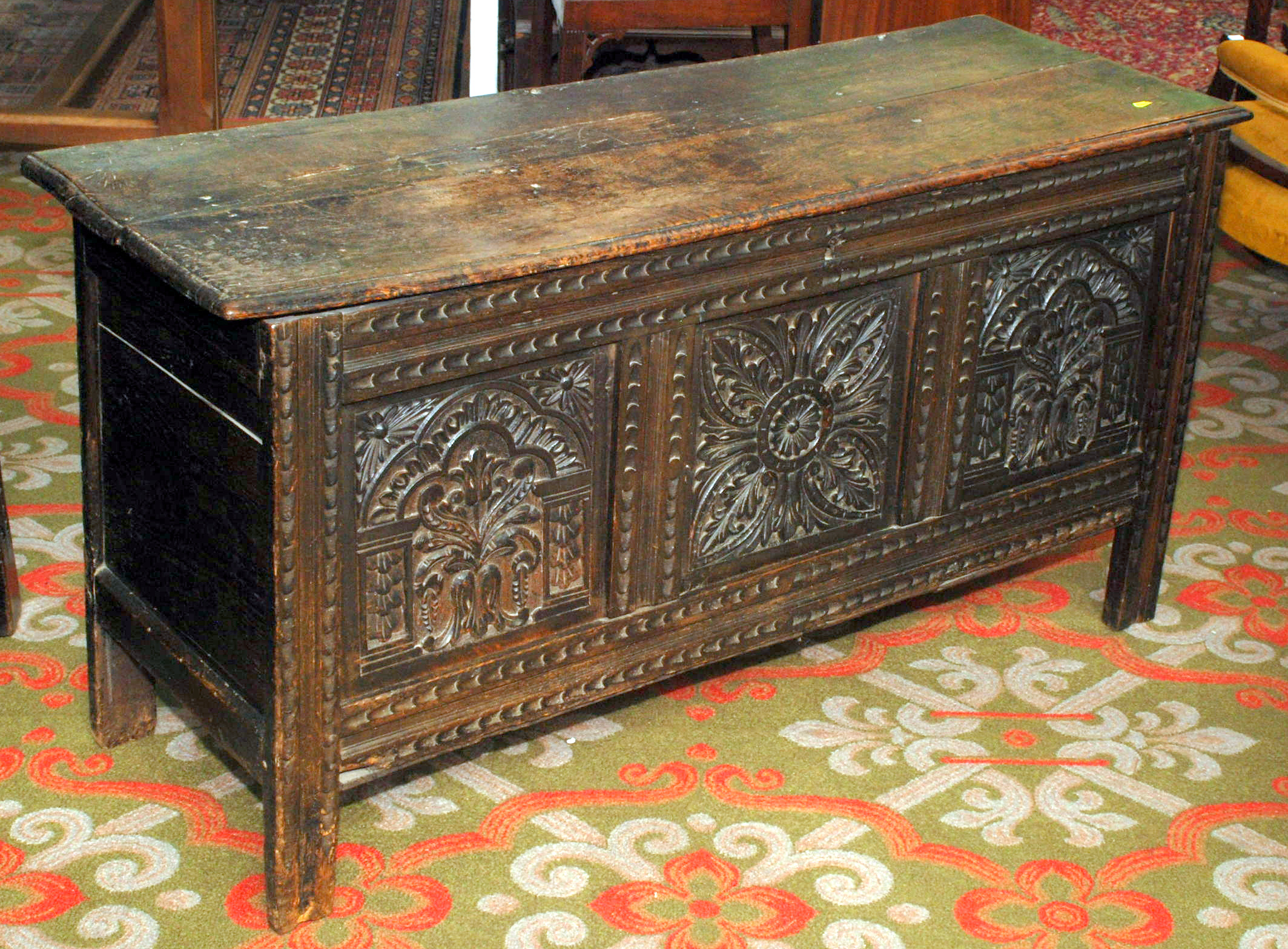 A 17th century oak joined chest, the boarded lid over three flower carved panels, the one at the
