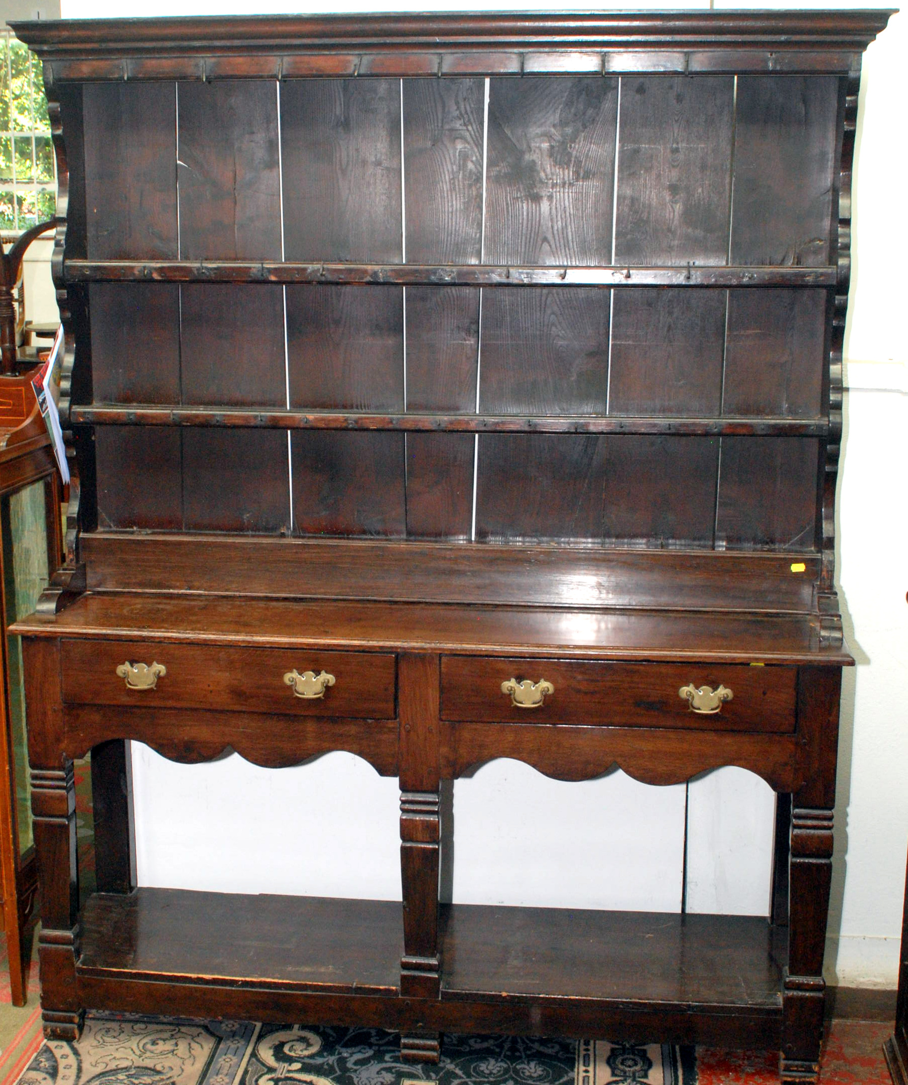 An 18th century oak dresser with open rack, the base with two drawers above shaped aprons and with