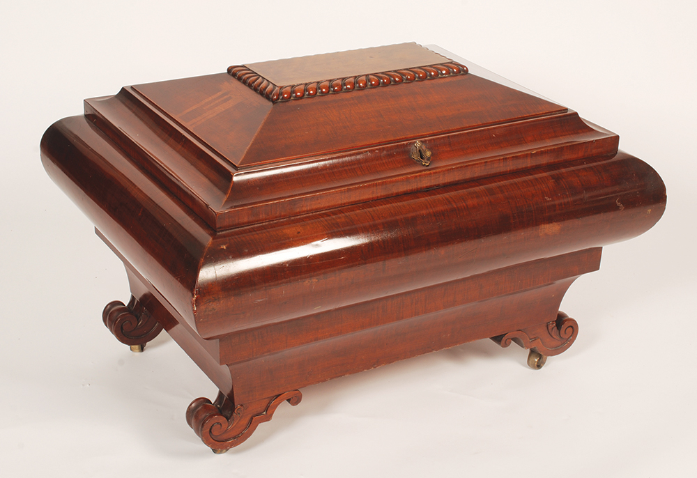 A good early Victorian mahogany wine cooler of curved sarcophagus form on carved scroll feet, the