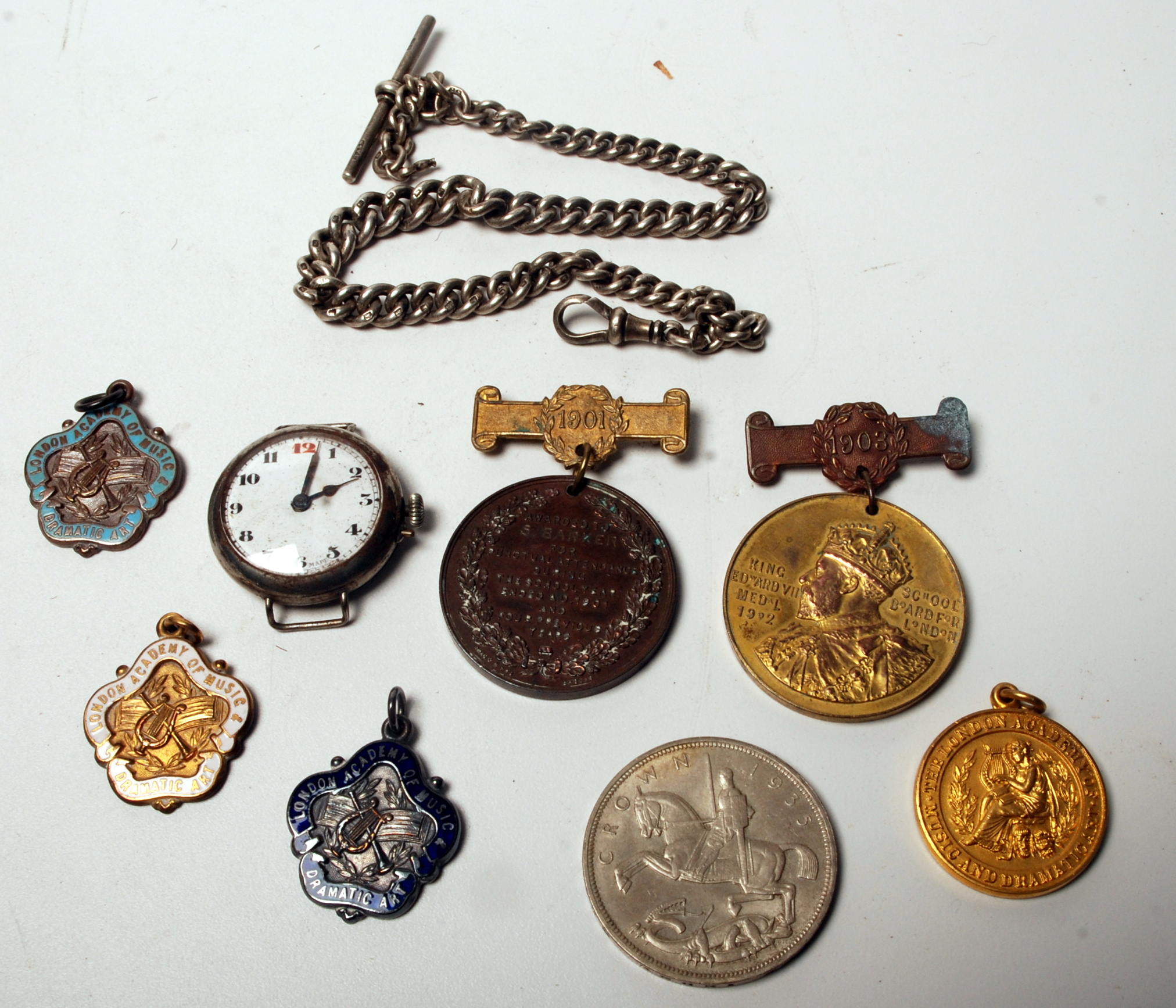 A 1935 crown, a silver watch chain, school medals and a trench watch.