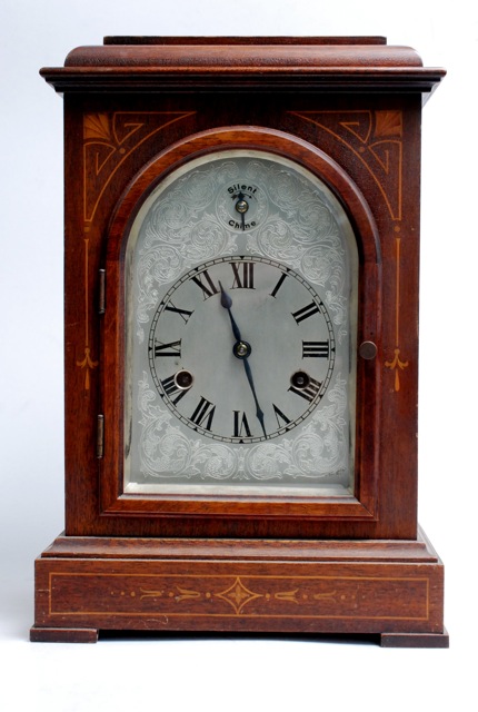 An early 20th century, inlaid mahogany, bracket clock with arched silvered dial.