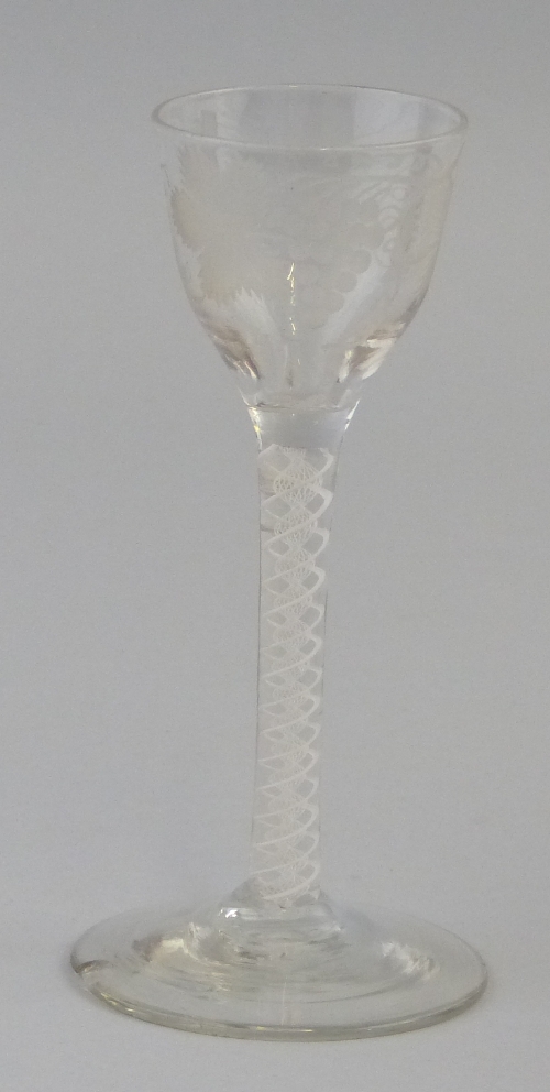 An 18th Century wine glass, the ogee bowl engraved with fruiting vines on double series opaque