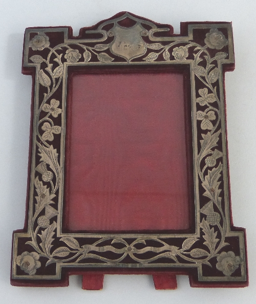 An Edwardian photograph frame, the oblong aperture in shaped surround pierced with scrolling