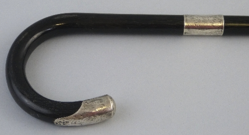 An early 20th Century ebonised walking stick, the crook shaped handle with chased silver terminal