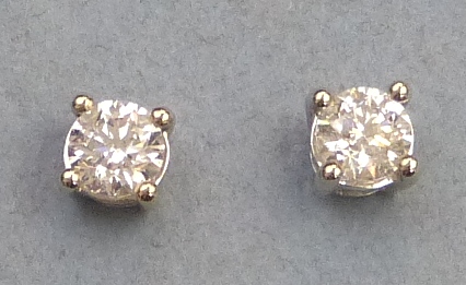 A pair of diamond stud earrings, each comprising a single stone (1.0ct total) claw set in 18ct