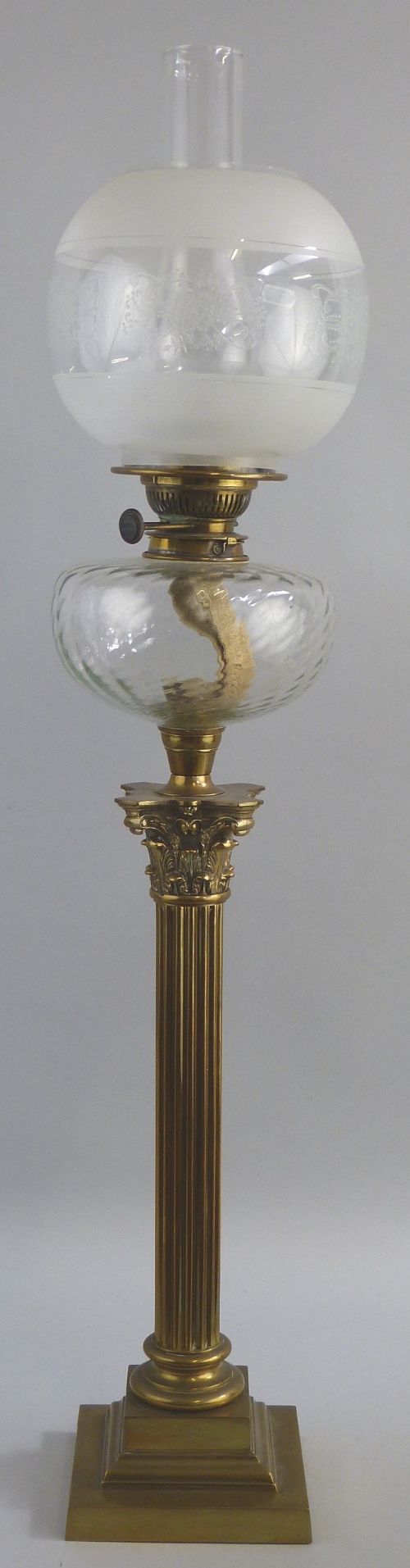 A table oil lamp, as a brass Corinthian column with stepped square base supporting a moulded clear