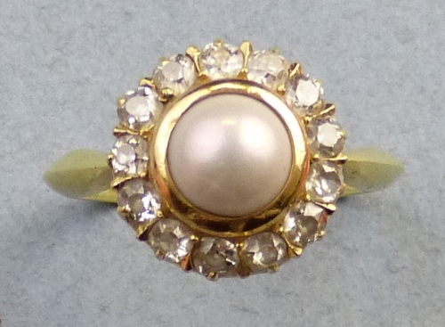 A pearl and diamond cluster ring, comprising a central pearl surrounded by diamonds on screw off