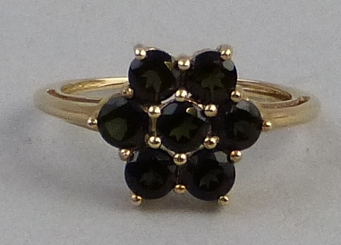 A green tourmaline cluster ring, the seven stones claw set in the form of a flowerhead on yellow