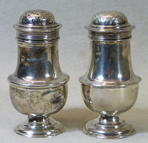 A pair of Edwardian pepperettes, of waisted pear form with pierced slightly domed lids raised on