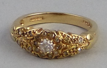 A diamond ring, comprising a central flowerhead of diamonds flanked to either side by leaf