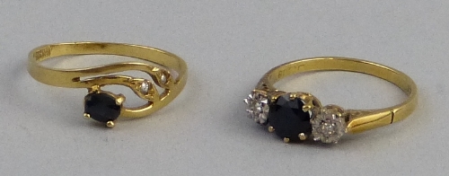 A sapphire and diamond ring, comprising central dark blue sapphire flanked to either side by