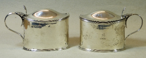 Two near matching mustard pots, of dished oval form with shell thumb piece on hinged domed lid