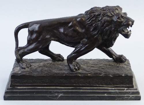 A 20th Century bronze figure of a lion, cast in a walking pose with mouth snarling on naturalistic