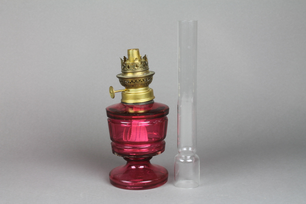 A Victorian cranberry faceted oil lamp with brass mounts and chimney 14