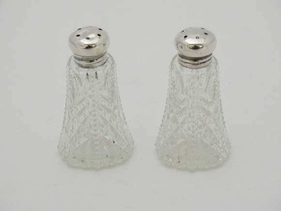 A pair of American cut glass pepperettes with Sterling silver tops. Moulded to glass base ' PAT. I