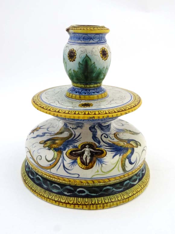 An Italian faience Ginori / Maiolica shaped candlestick, decorated with grotesque winged figures