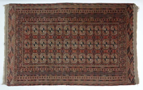 Rug Carpet : An antique Turkeman carpet , the madder field with 12 rows of 3 guls and minor guls , 4