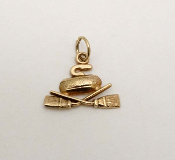 Curling : A Continental gold pendant charm formed as a curling stone and crossed brushes.  Marked