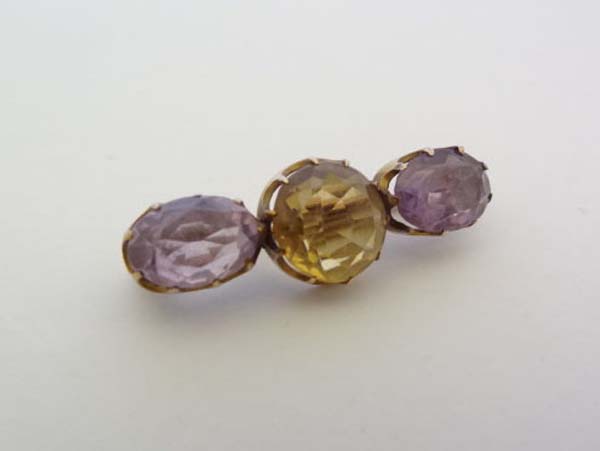 A yellow metal bar brooch set with central citrine flanked by 2 amethysts 1 1/4" wide