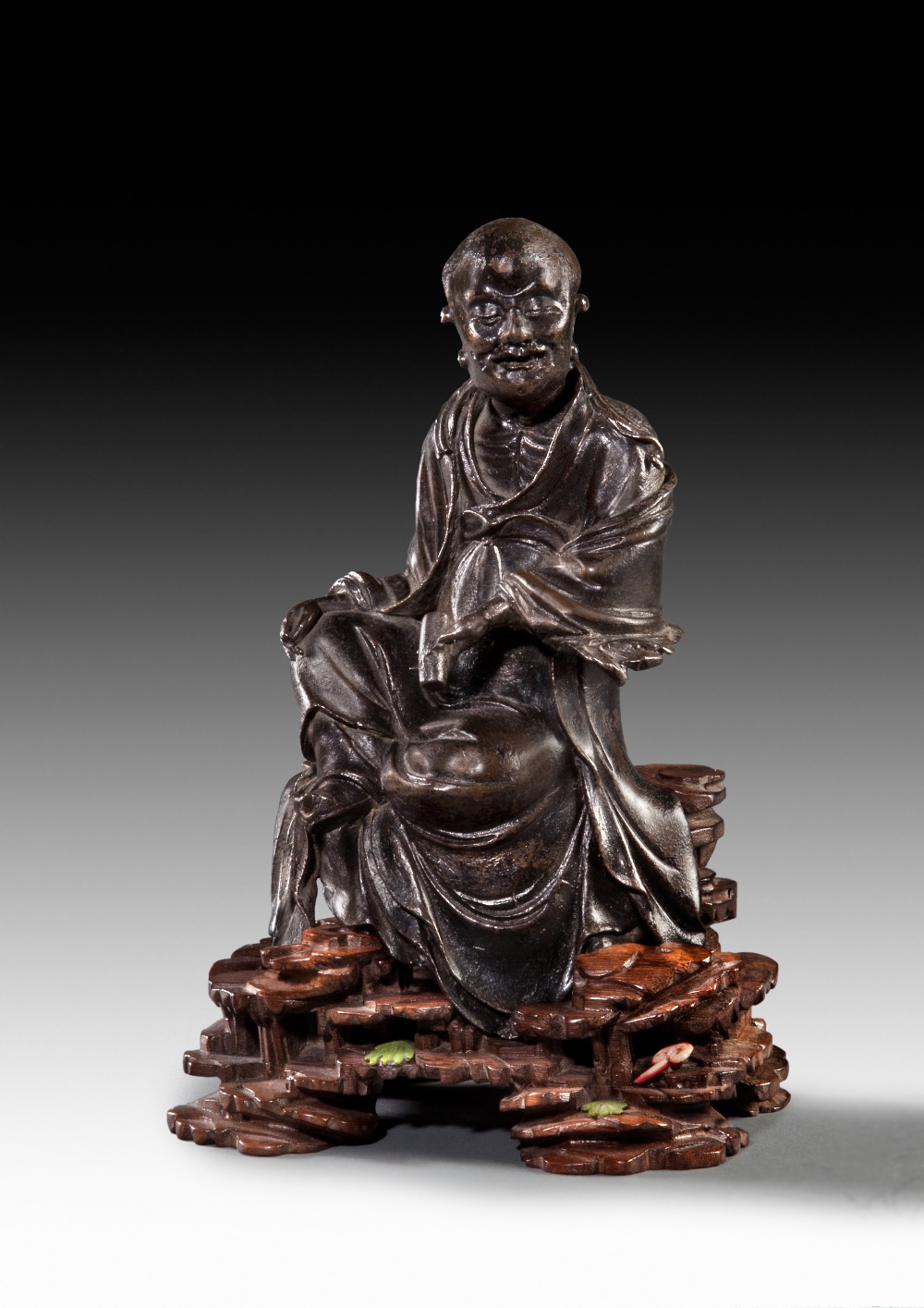 A BRONZE FIGURE OF LUOHAN, LATER MING DYNASTY. H: 20.3 cm.
Seated, with his right hand resting on