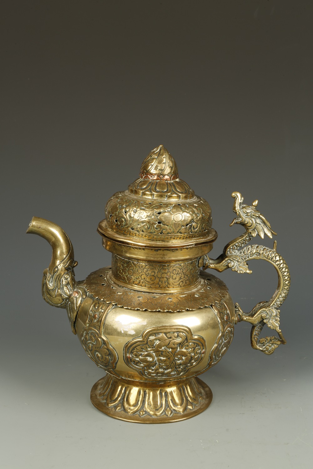 A TIBETAN COPPER AND BRASS RITUAL EWER, with a dragon handle and mask spout, the body with panels