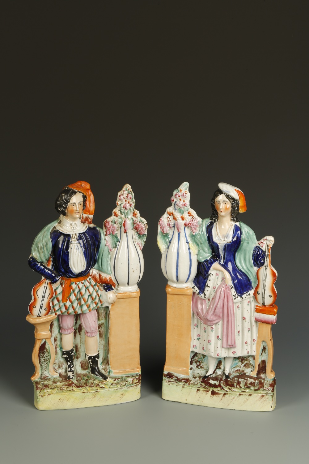 A PAIR OF STAFFORDSHIRE FLAT-BACK FIGURES OF A LADY AND GENTLEMAN with blue jackets, holding