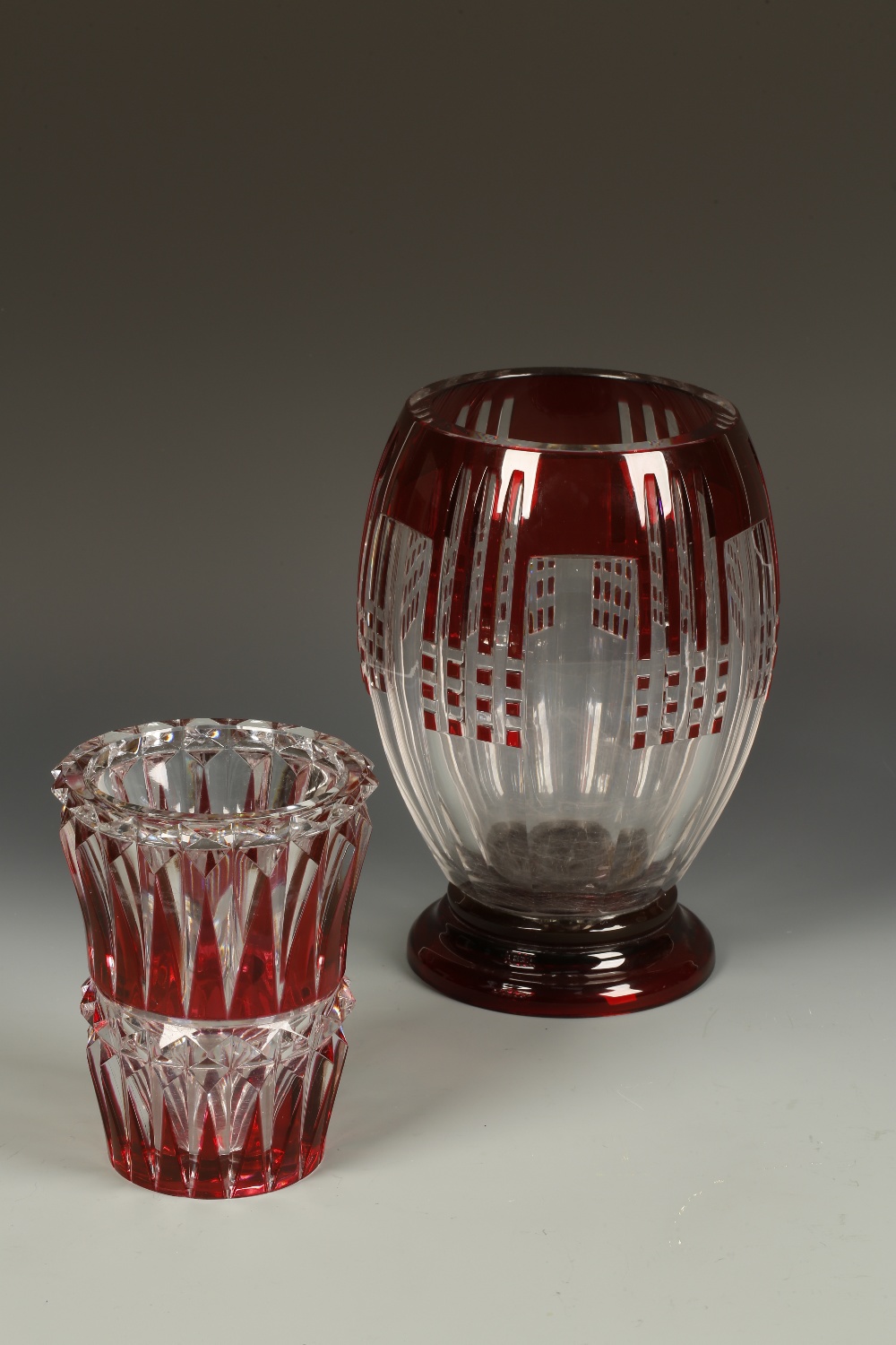 VAL ST. LAMBERT: A RED OVERLAID AND CUT CLEAR GLASS VASE with geometric panel-cut decoration, on a