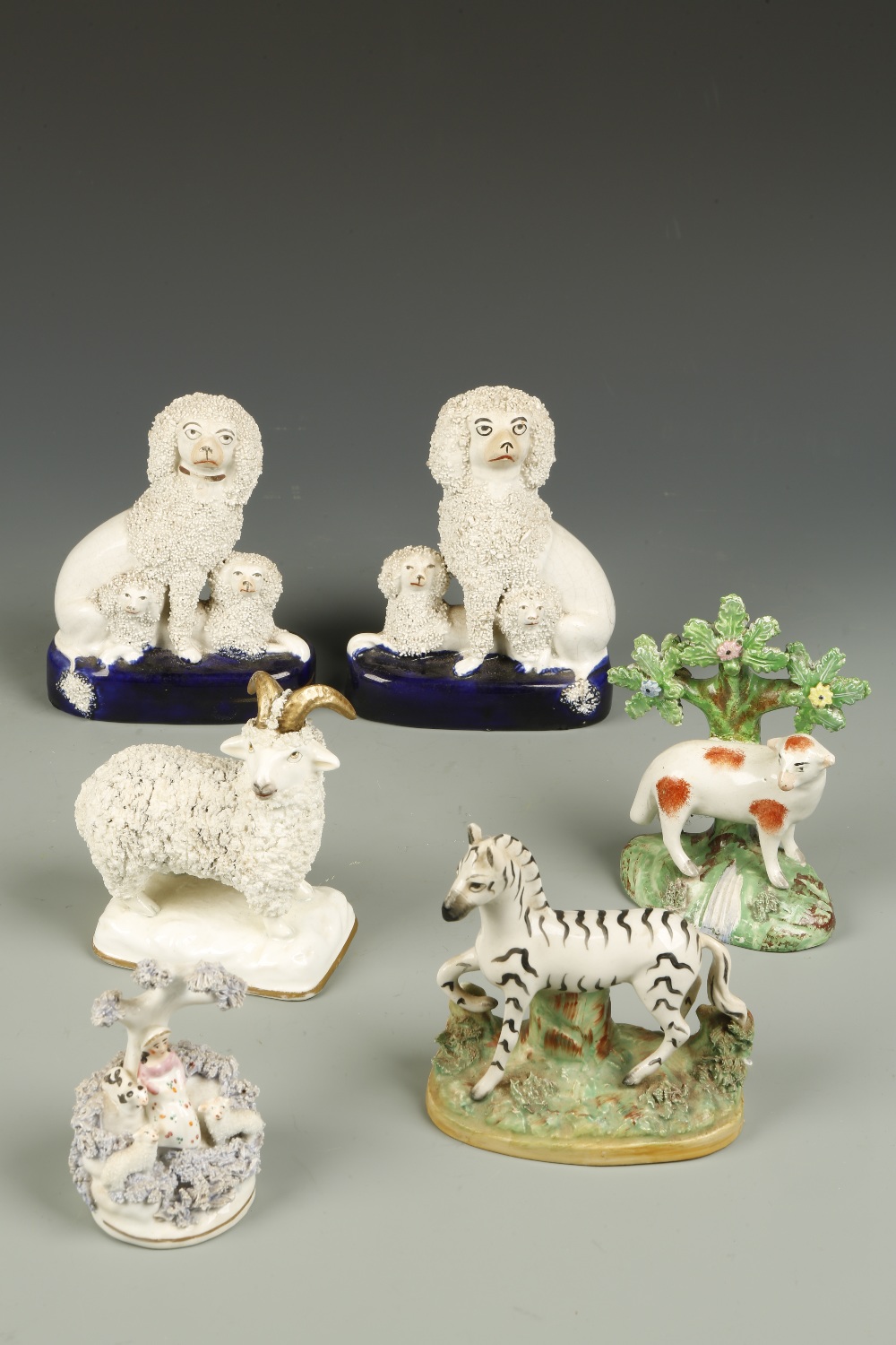 A PAIR OF STAFFORDSHIRE POODLE ORNAMENTS, each with an adult poodle and two puppies, on blue glazed
