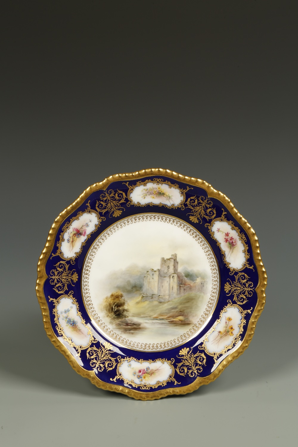 A ROYAL WORCESTER PLATE painted to the centre with a view of Brougham Castle, painted by John