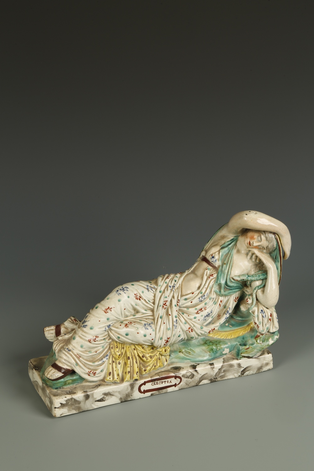 A RALPH WOOD TYPE FIGURE OF CLEOPATRA, the figure lying recumbent on a green and marble effect