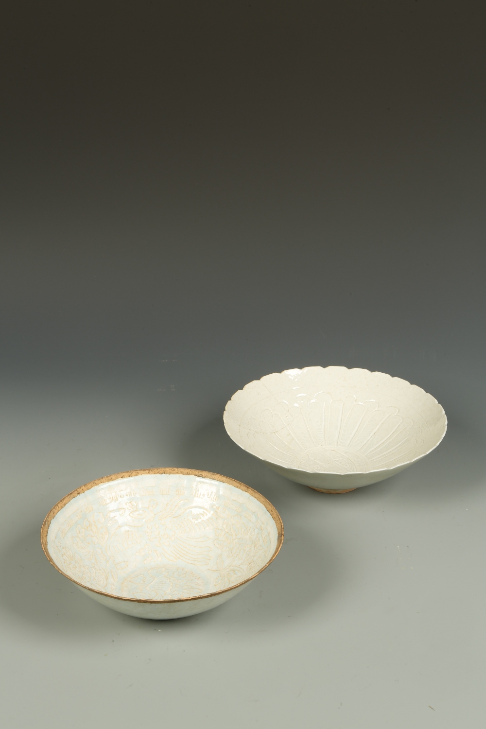 TWO CHINESE QINGBAI TYPE BOWLS: one moulded with phoenix amongst foliage, beneath a bluish-grey