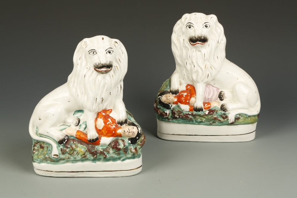 A PAIR OF STAFFORDSHIRE FLAT BACK FIGURES OF A LION seated over a body wearing a red tunic,