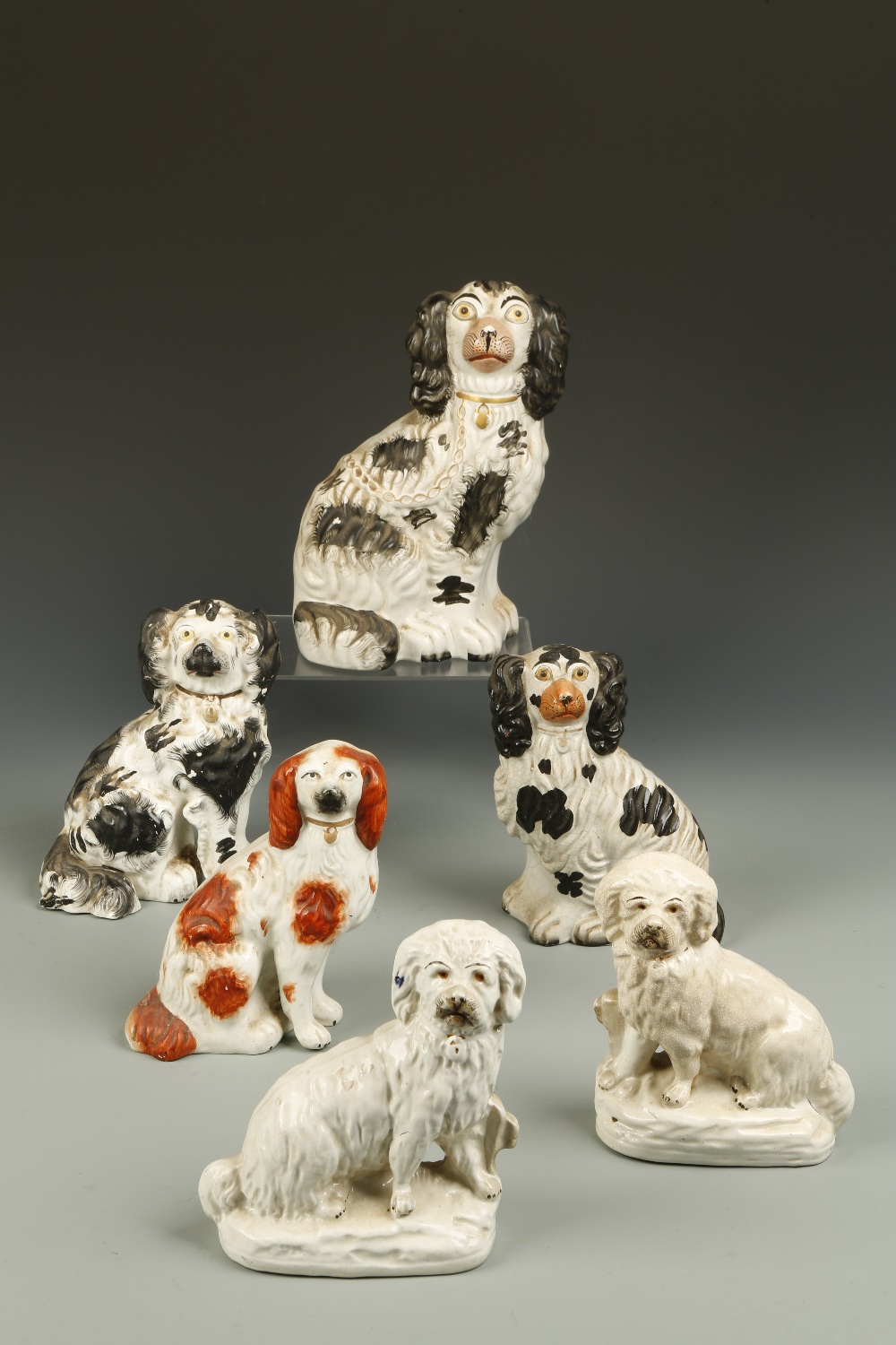A COLLECTION OF FOUR STAFFORDSHIRE POTTERY SPANIELS, three with black coats, and a pair of similar