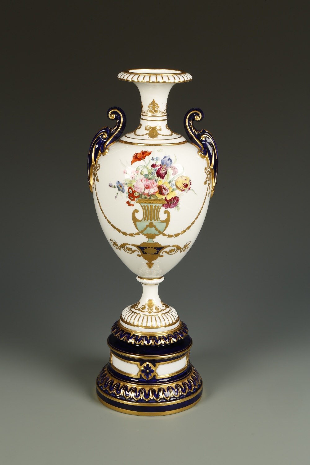 A ROYAL WORCESTER VASE of urn form, raised on a circular pedestal base, the white ground painted