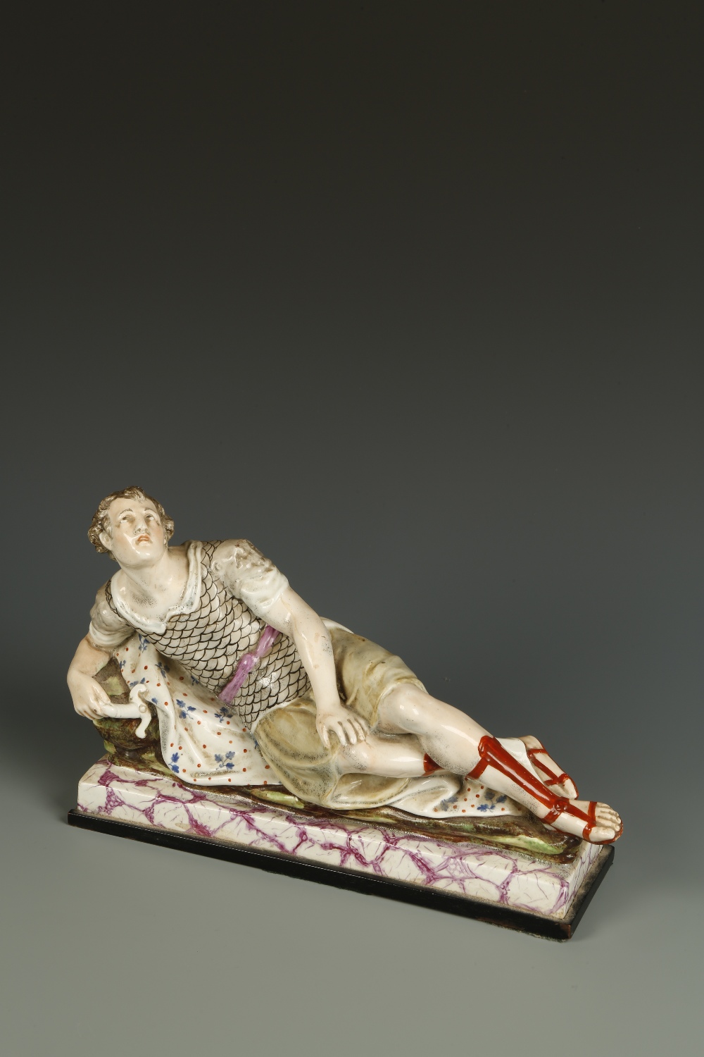A RALPH WOOD TYPE FIGURE OF MARK ANTONY lying on a mottled and marbled effect base, 12"" wide. See