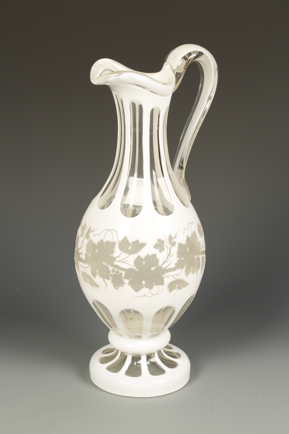 A VICTORIAN BOHEMIAN STYLE WHITE OVERLAID CLEAR GLASS WATER JUG with panel-cut neck and vine leaf