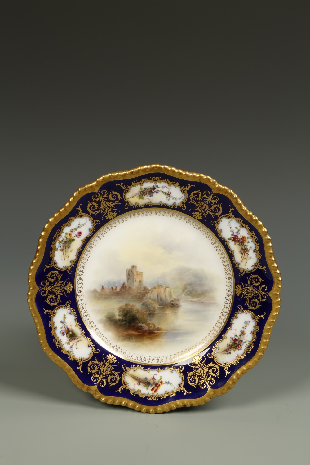 A ROYAL WORCESTER PLATE painted to the centre with a scene of Bothal Castle, by John Stinton,