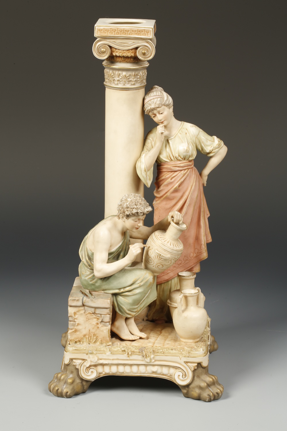 A ROYAL DUX GROUP of a seated classical man painting an urn, with a lady looking on, leaning against