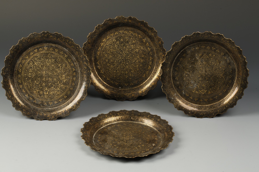 A SET OF FOUR ISLAMIC `DAMASCENED` PLATES, with foliate borders and decorated with scrolling