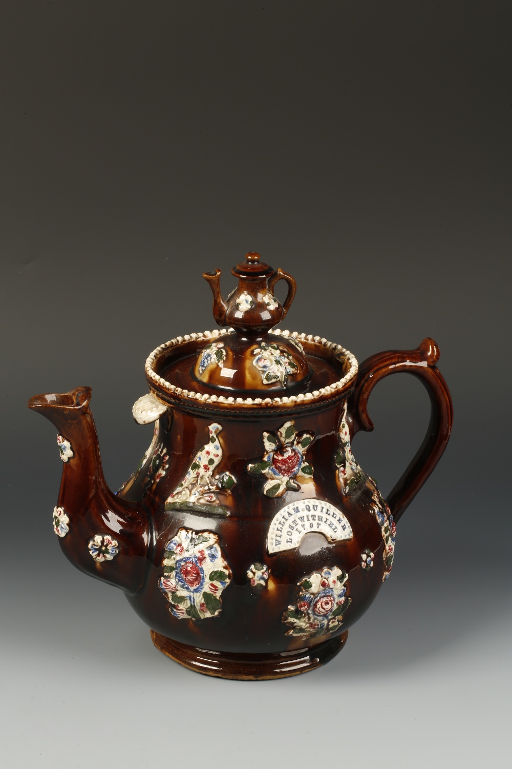 A MEASHAM TYPE POTTERY BARGEWARE TEAPOT and cover decorated in relief with floral rosettes and