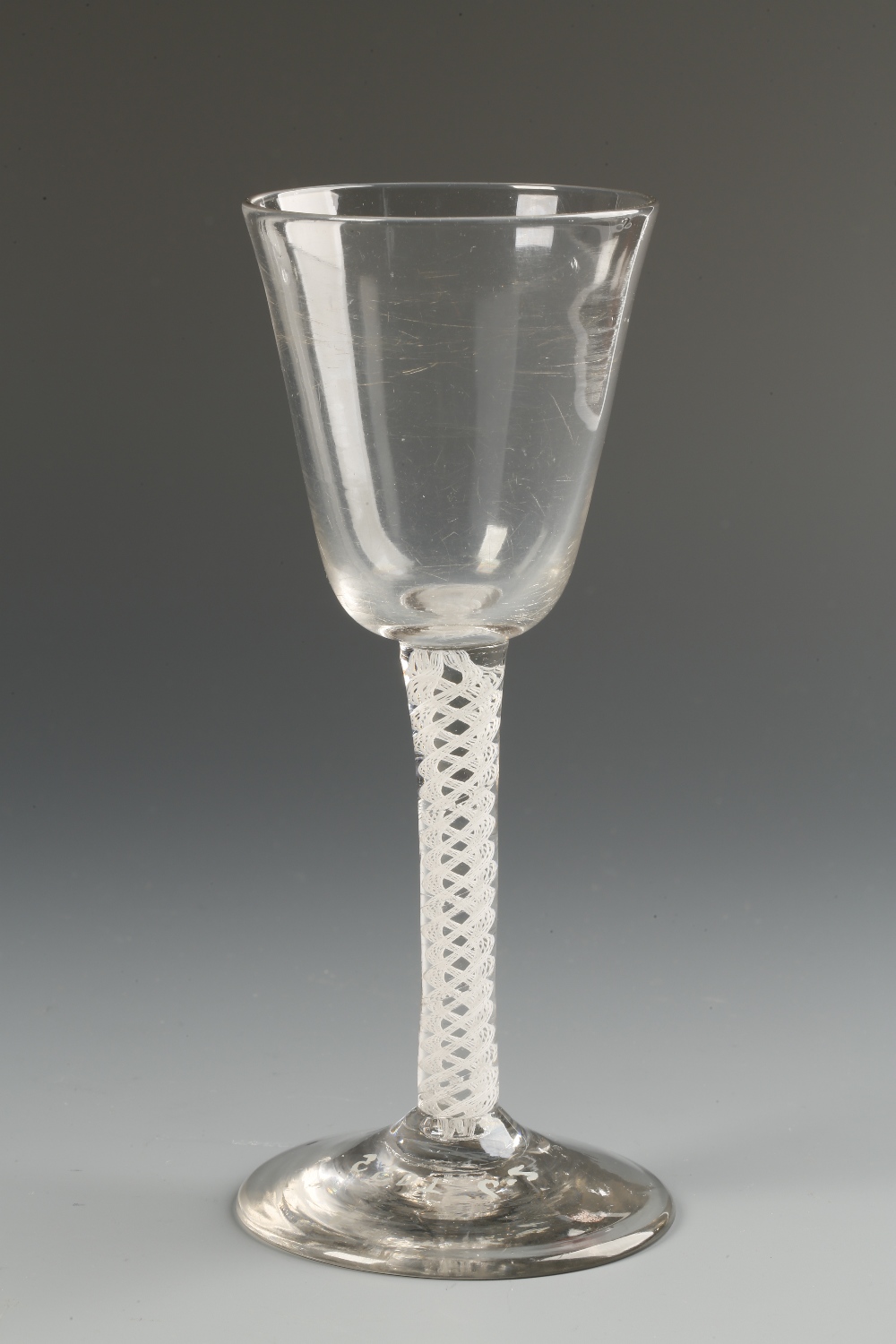 AN 18TH CENTURY WINE GLASS with a plain straight-sided bowl on a double air-twist stem on a circular