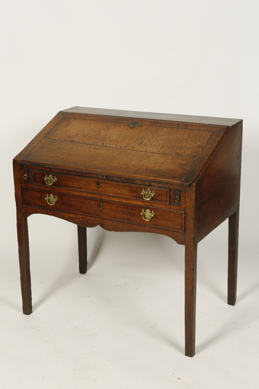 A GEORGE III OAK WRITING DESK, the sloping fall enclosing a fitted interior with short drawers and