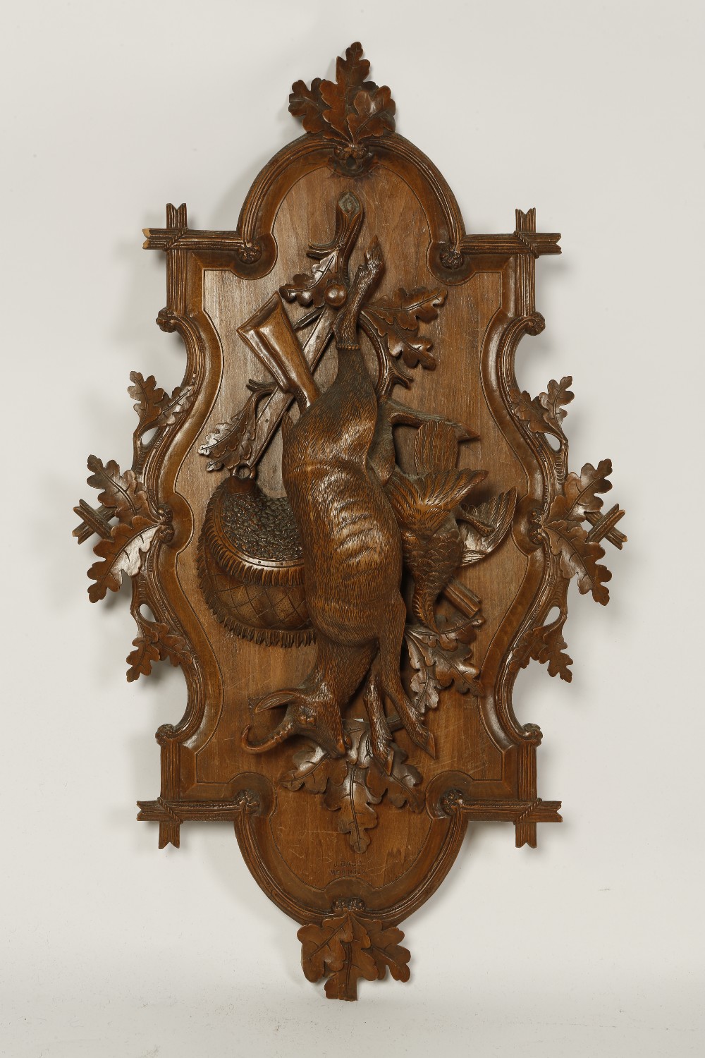 A 19TH CENTURY SWISS CARVED WALL PANEL with a shaped scrolling background decorated with oak leaves,