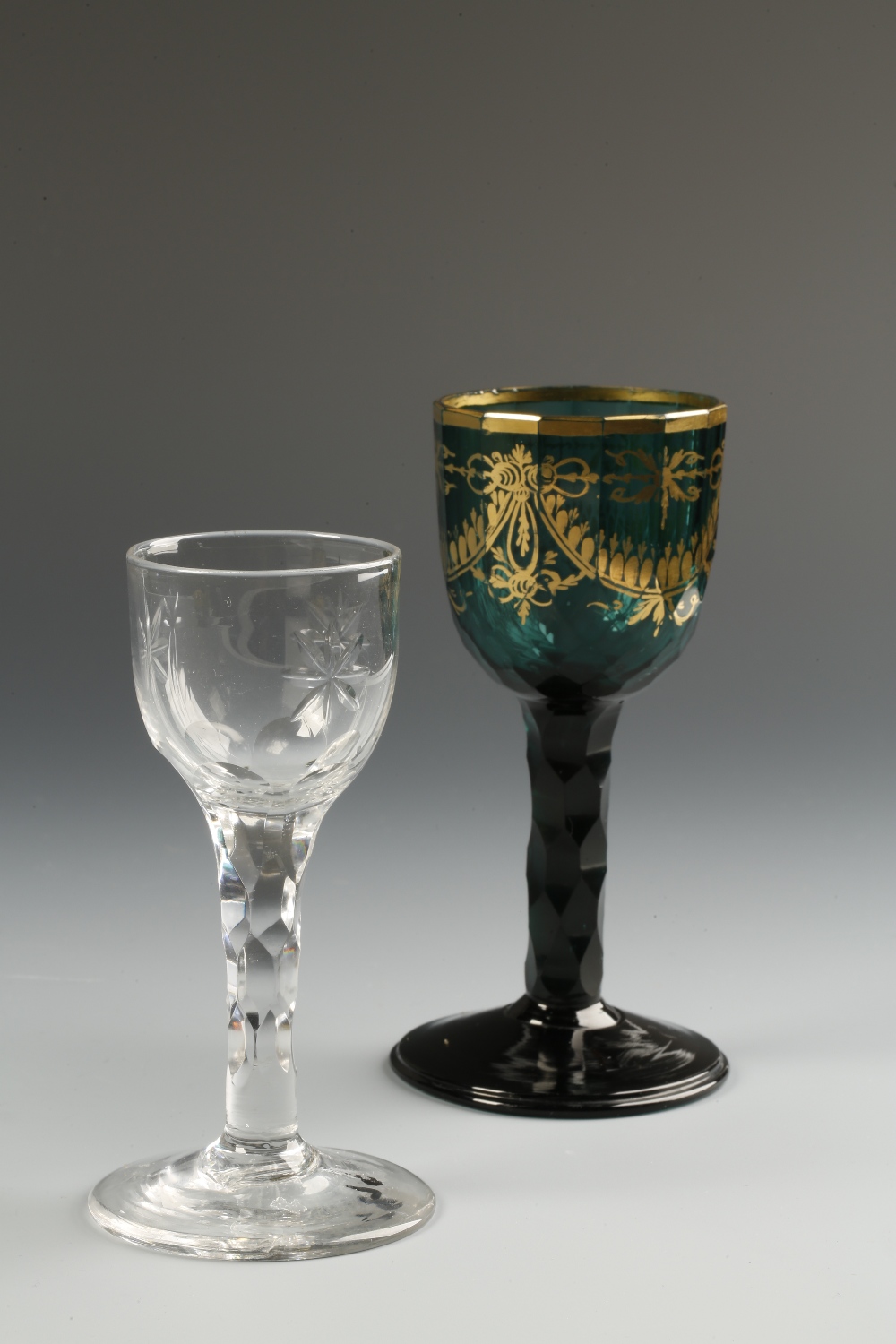 A 19TH CENTURY "EMERALD" GREEN GLASS WINE GOBLET, the faceted bucket-shaped bowl with gilt rim and