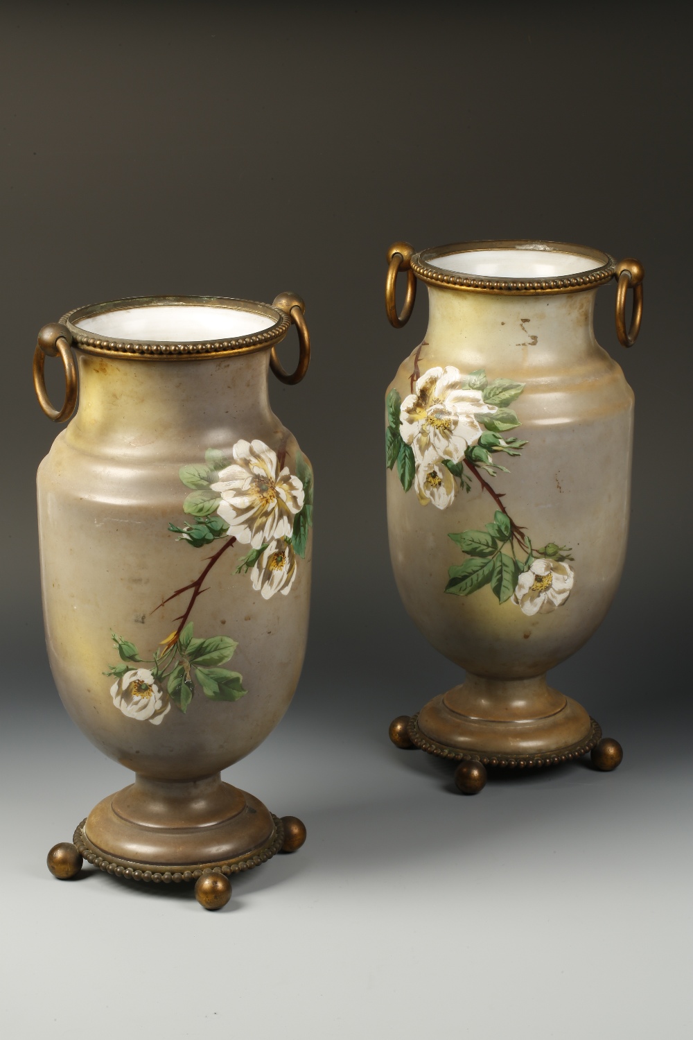 A PAIR OF VICTORIAN PAINTED WHITE GLASS VASES of bellied form decorated with roses in bloom