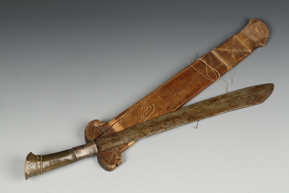 AN INDIAN KLEWANG DAGGER, the handle probably rhino horn, with silver-metal mounts and carved with