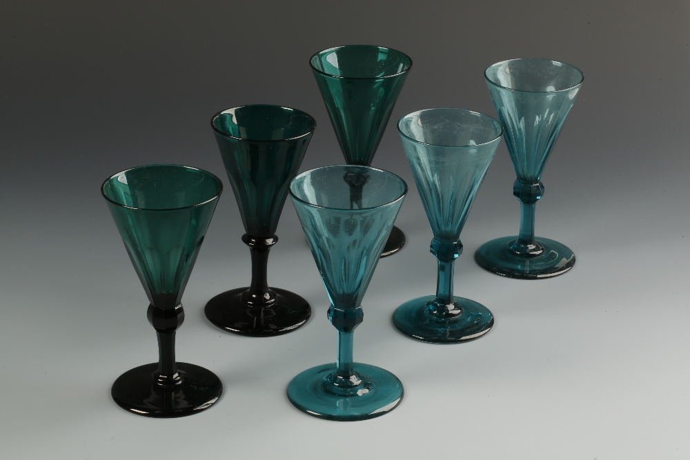 A MATCHED SET OF SIX GREEN AND PALE GREEN WINE GLASSES with tapering panel-cut bowls, on faceted