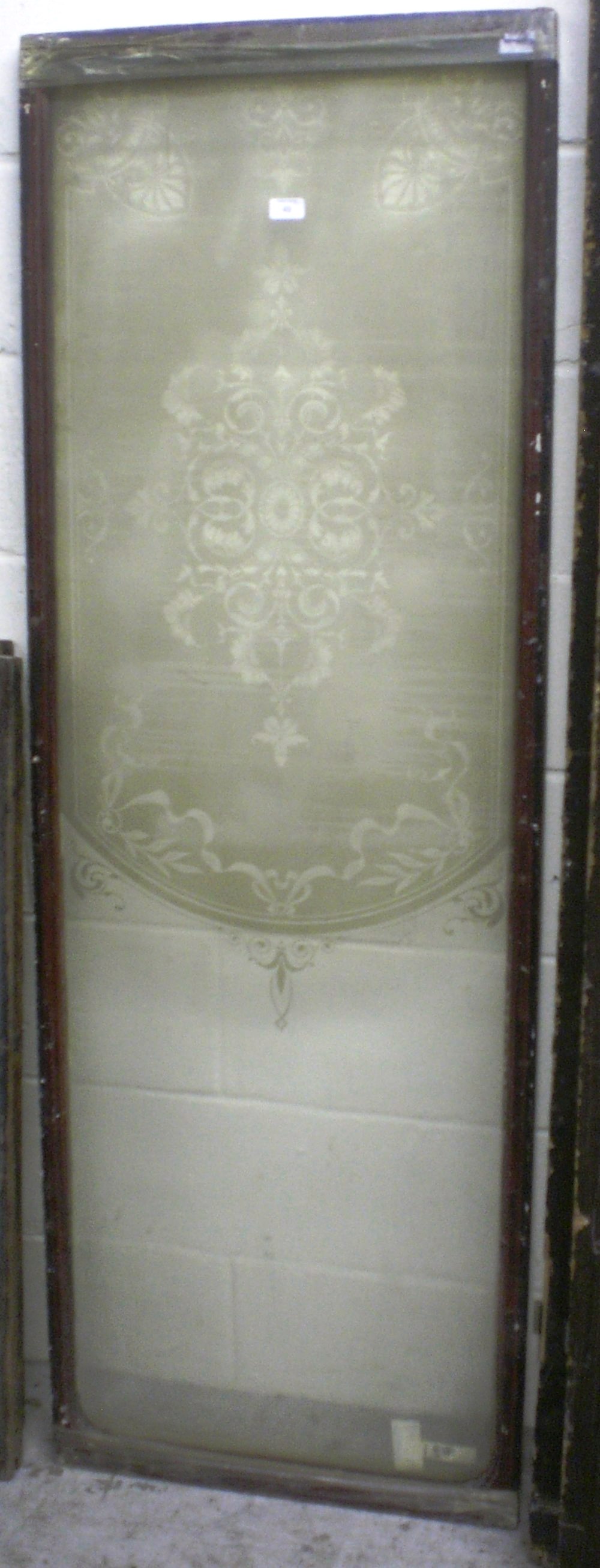 A large etched window with decorative scrolling patterns